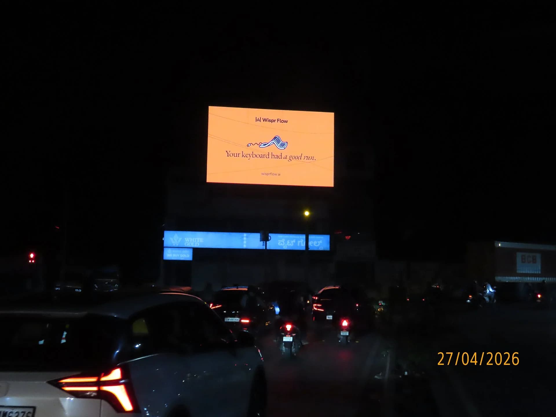 Illuminated billboard glowing orange above night traffic